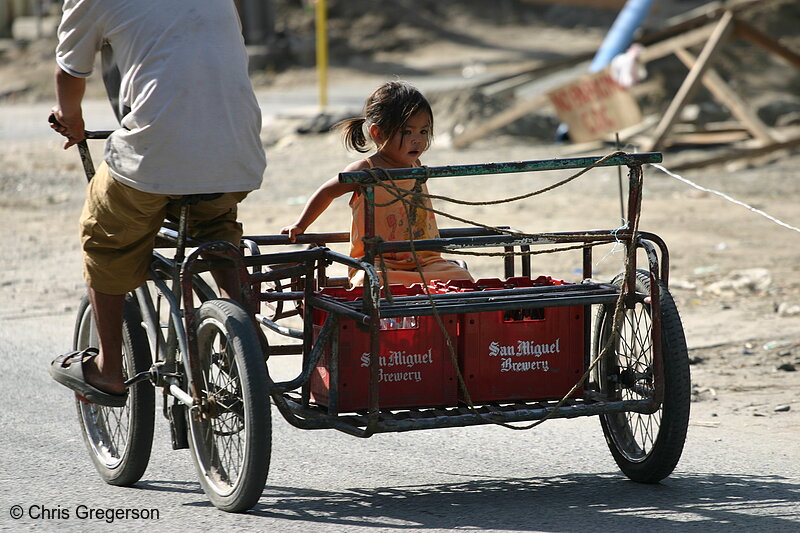 Photo of Toddler Being Carried on a Moving Tricycle Along With Two Red San Miguel Beer Cases(5274)