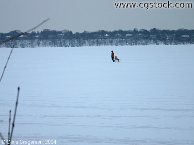 Man Walking Dog on Frozen Lake
