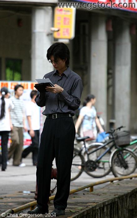 Man Standing, Reading on Sidewalk in China