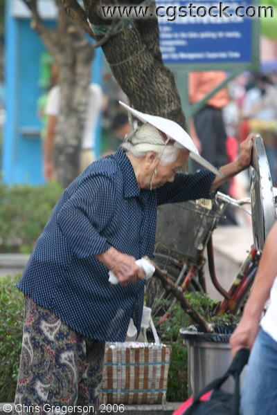 Elderly Chinese Woman Rummaging in Trashcan