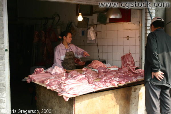 Woman Butcher Selling Meat to a Customer in Beijing