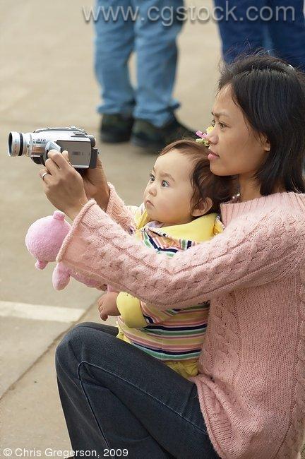 Mother and Child Using Camcorder at a Parade